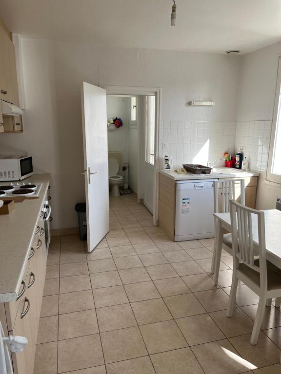 a kitchen with a table and a door to a room at appartement spacieux et lumineux proche de la plage in Quimiac
