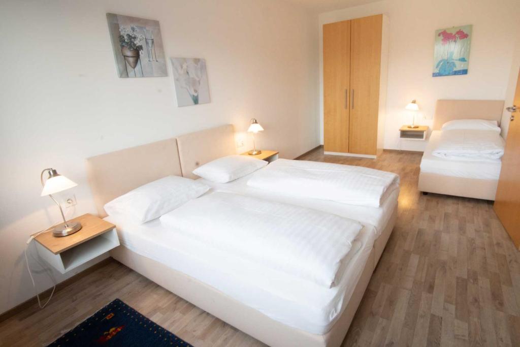 1 dormitorio blanco con 2 camas y 2 lámparas en Family XL - Ferienwohnungen, en Lutzmannsburg