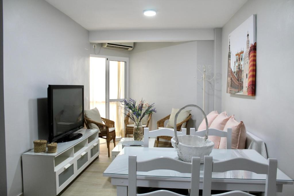 uma sala de estar com uma televisão e uma mesa e cadeiras em WISH SUITE BASILICA em Sevilha