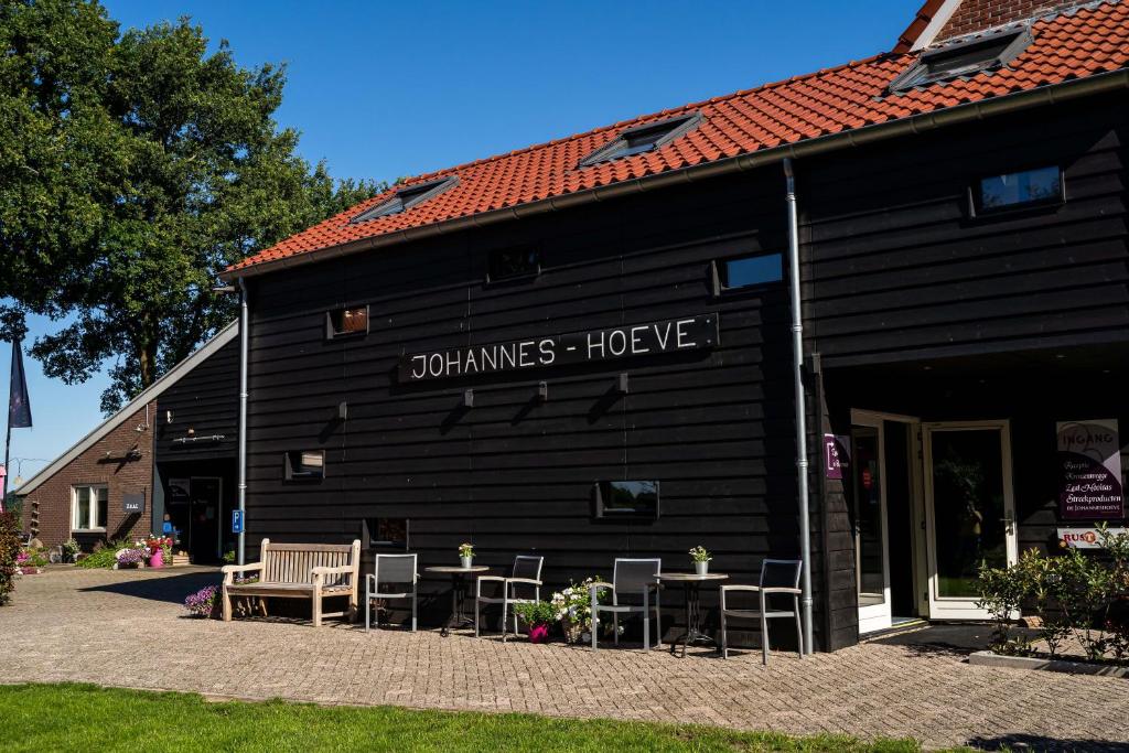 ein schwarzes Gebäude mit Stühlen und Tischen davor in der Unterkunft De Johanneshoeve in Westerhaar-Vriezenveensewijk