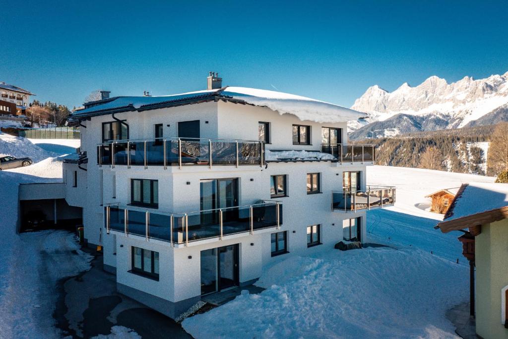 een wit gebouw in de sneeuw met bergen bij Ski In/Ski Out Appartement Jagahütt'n by Schladmingurlaub in Schladming
