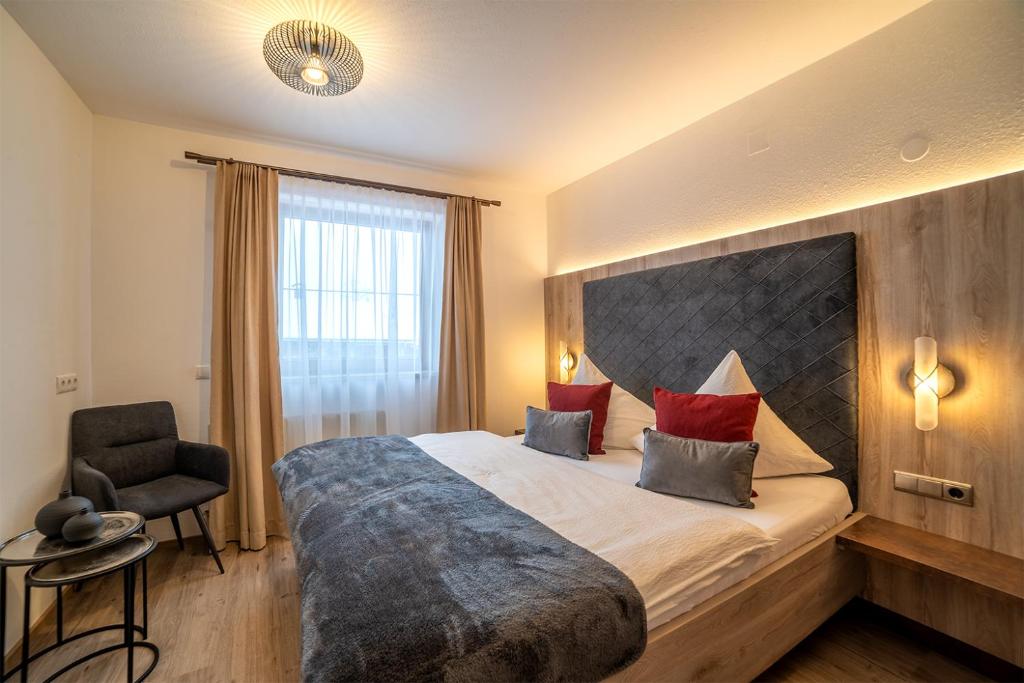 ラムサウ・イム・ツィラータールにあるLandhaus Schiestlの大きなベッドと椅子が備わるホテルルームです。