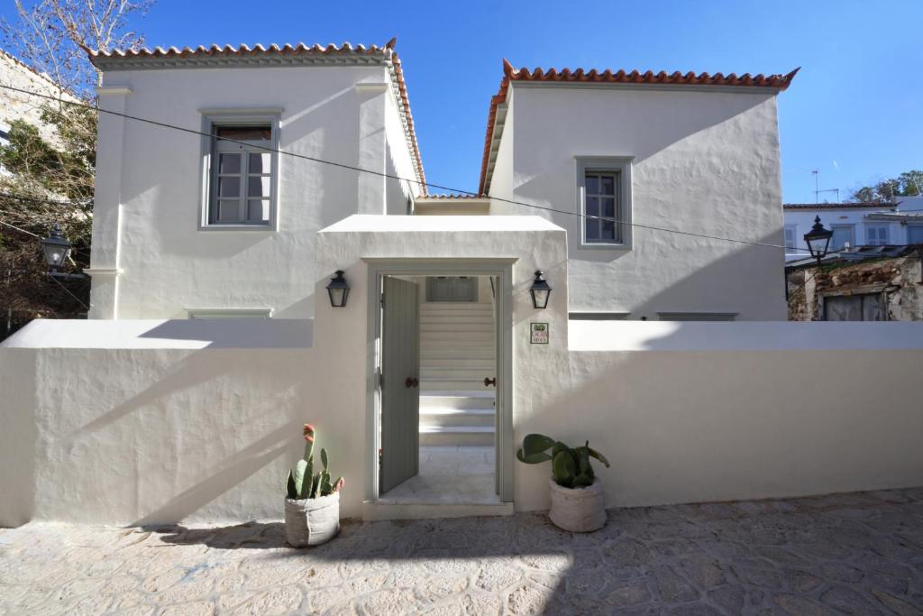 a white house with a door and a potted plant at Cactus Hydra - Art Apartments in Hydra