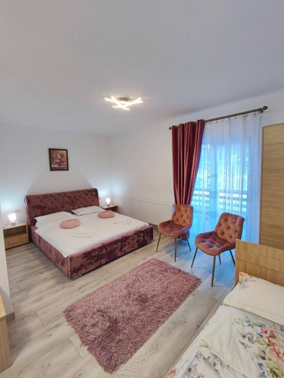 a bedroom with two beds and two chairs at Vila CASA HATERE in Moisei