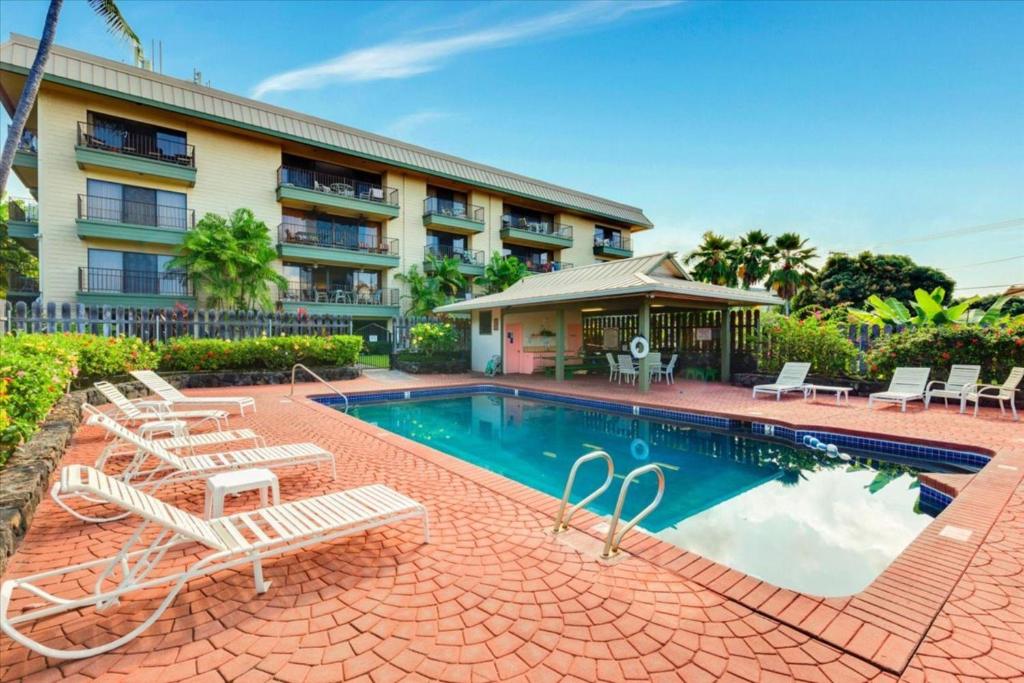 a swimming pool with lounge chairs and a hotel at Kahaluu Bay Village 201 by Casago Kona - Snorkeling, Surfing and Spaciousness in Kailua-Kona