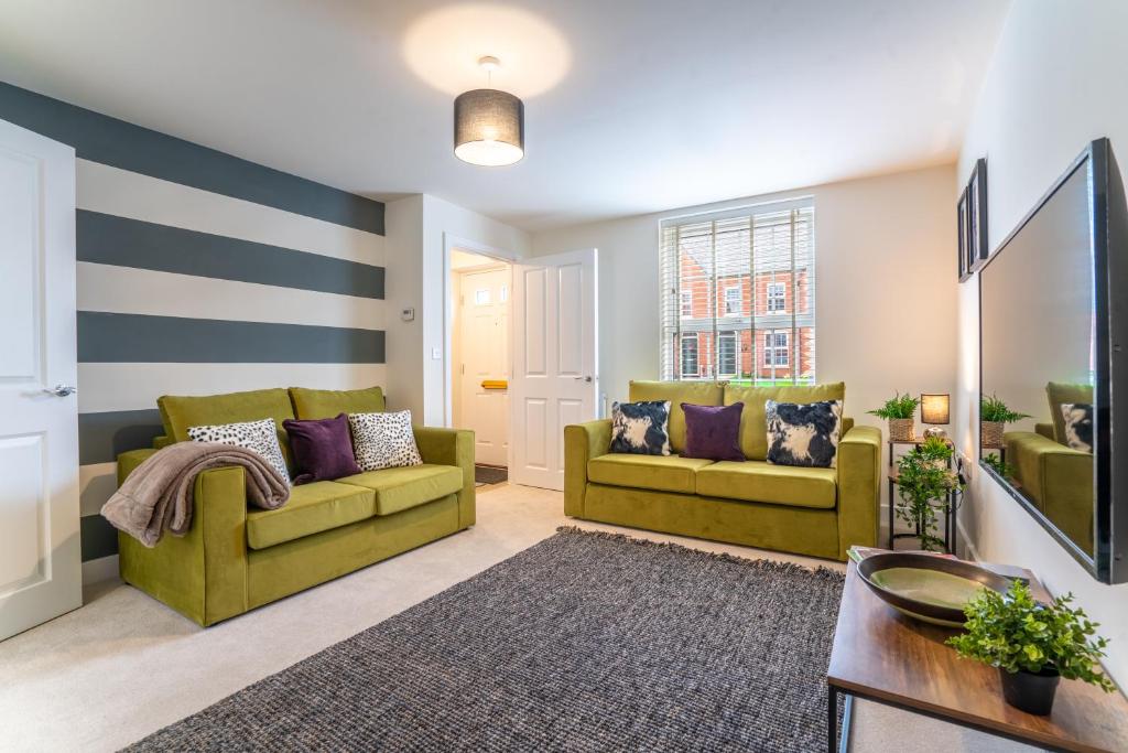 uma sala de estar com 2 sofás verdes e almofadas roxas em Saltbox Stays - Modern 3 Bed with off-street parking for 2 cars, fast Wifi, sleeps 6 em Ashby de la Zouch