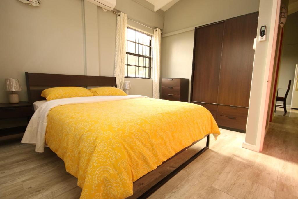 a bedroom with a large bed with a yellow blanket at Veronica's - Breathe Easy in Gros Islet