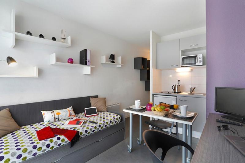 um pequeno quarto com uma cama e uma mesa em Résidence Néméa Tolosa em Toulouse
