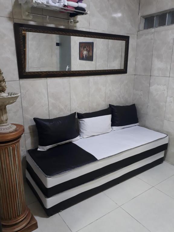 a bed with black and white pillows and a mirror at Casa Inteira aconchegante com garagem Próximo ao Aeroporto in Lauro de Freitas
