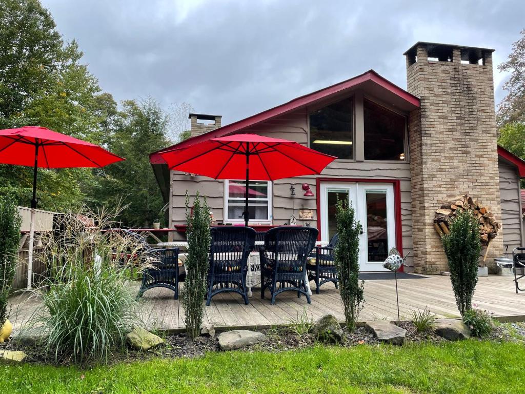 ein Haus mit roten Sonnenschirmen, Tischen und Stühlen in der Unterkunft Roscoe Cabin Pet friendly in Roscoe