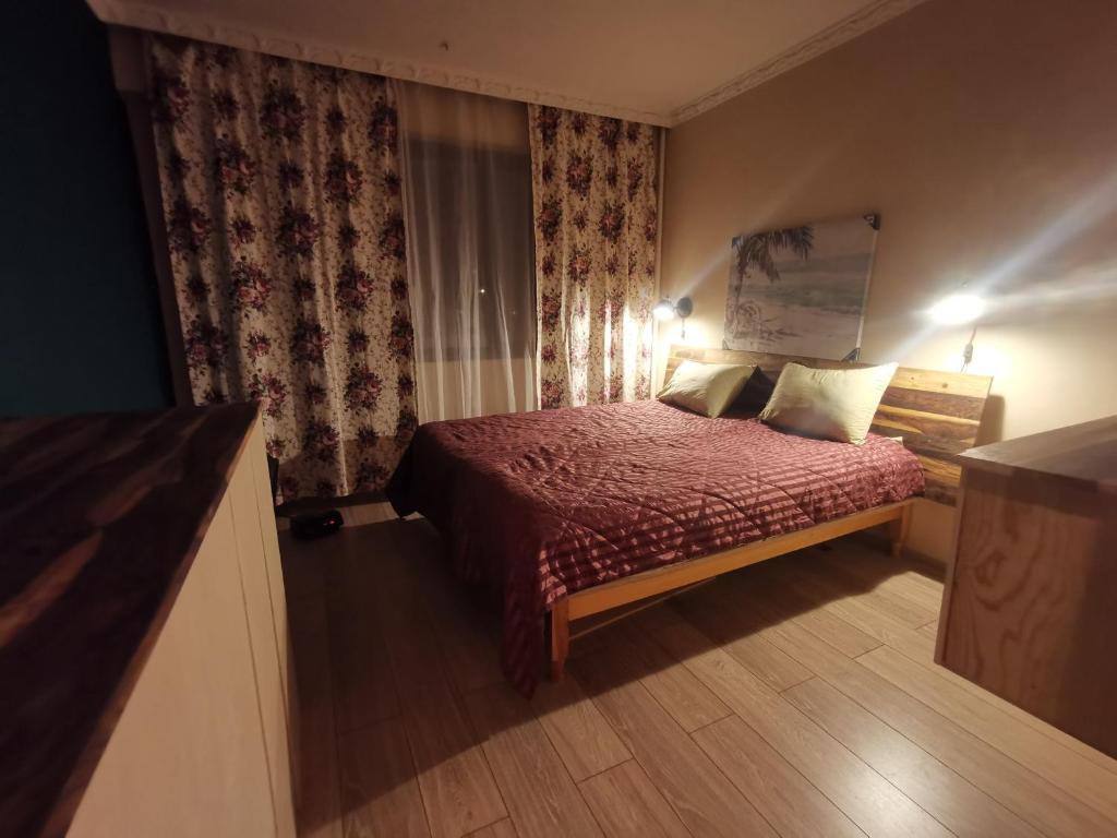 a small bedroom with a bed with a red comforter at Homey art apartment next to Drujba lake Metro stations and bul.Tsarigradsko Shose in Sofia