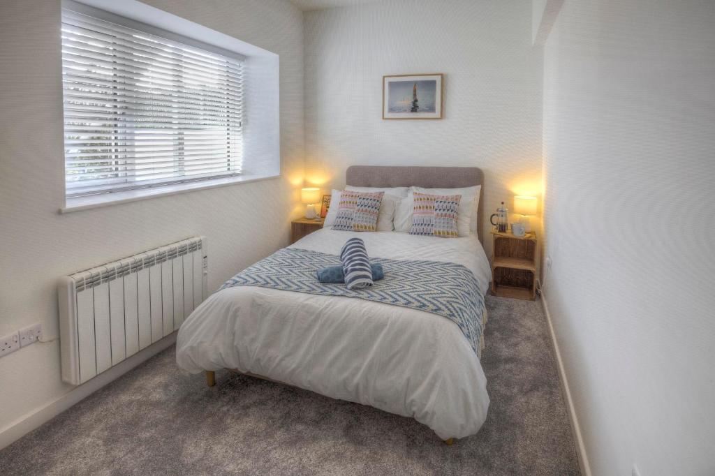 a bedroom with a bed with two pillows and a window at The Swell, Rhosneigr - Ground floor 2 bed With Parking in Rhosneigr
