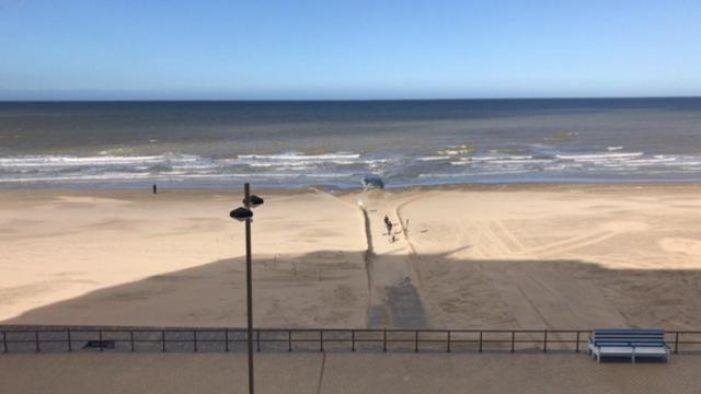 een zandstrand met een bank en een straatlicht bij Anaconda in Middelkerke