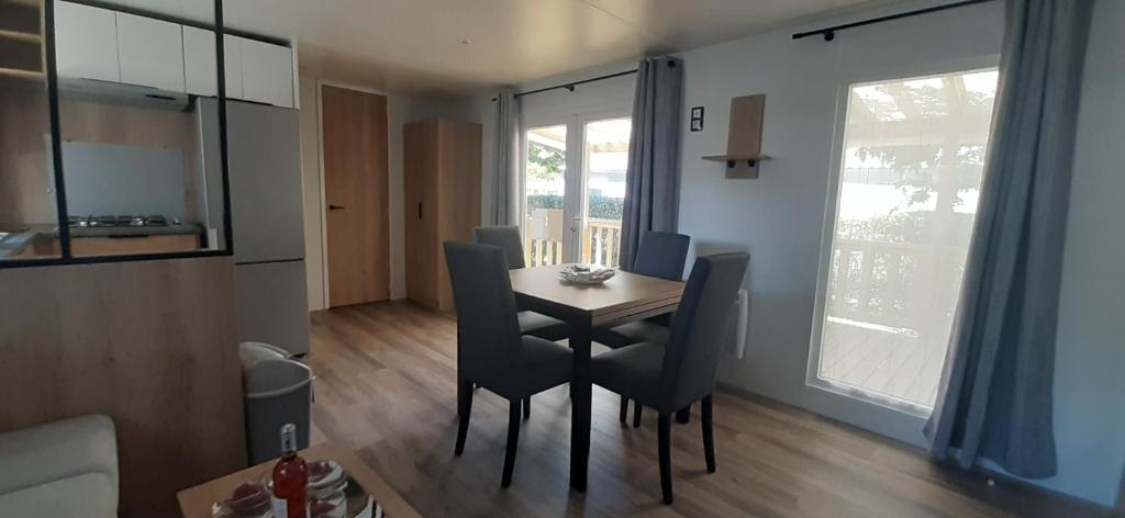 a dining room with a table and chairs in a room at Mobil-home de charme dans les Landes, neuf, tout équipé in Gastes