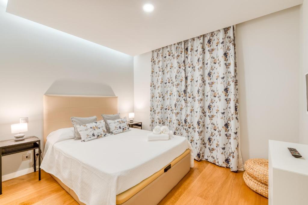 a white bedroom with a bed and a curtain at Casa da Praia in Caniço