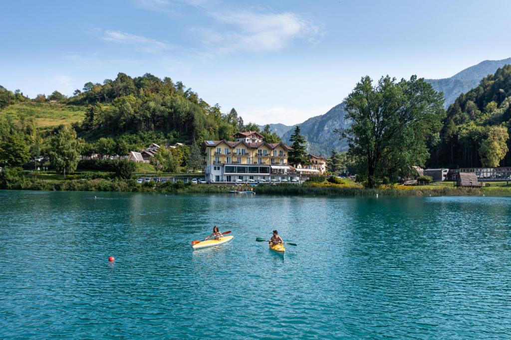 two people kayaking on a lake in front of a house at Panoramic Hotel San Carlo Ledro in Ledro