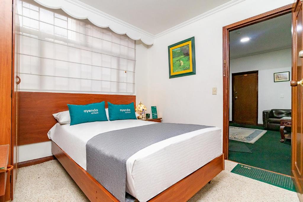ein Schlafzimmer mit einem großen Bett mit blauen Kissen in der Unterkunft Ayenda Americano in Bogotá