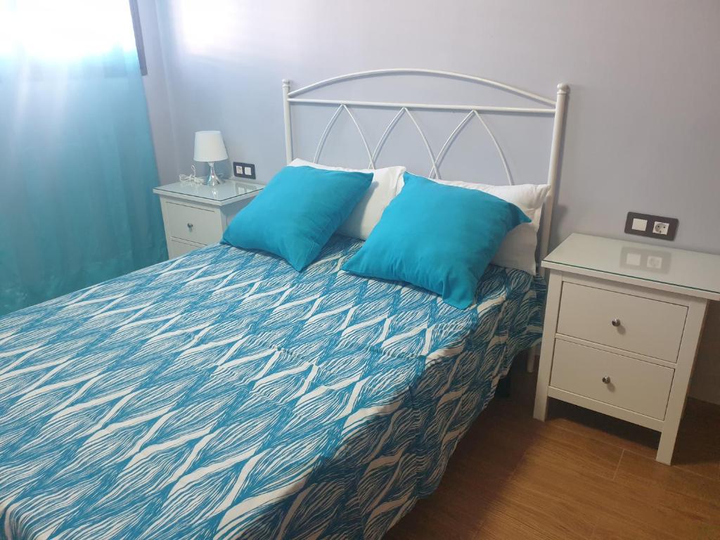1 cama con 2 almohadas azules en una habitación en Casa Rosita, en Puerto del Carmen