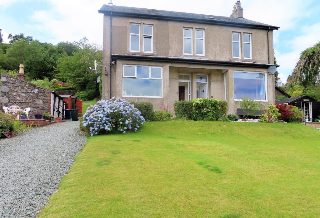 a house with a large lawn in front of it at Kames View Apartment in Tighnabruaich
