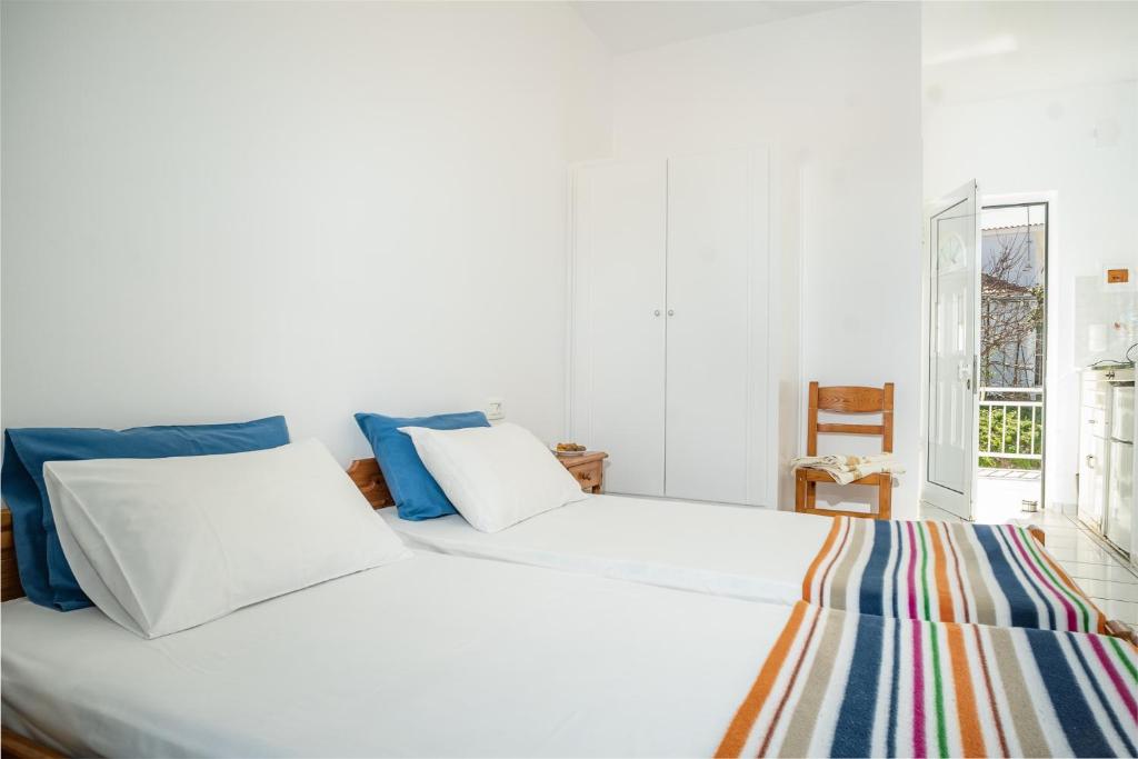 a white bed with blue pillows in a bedroom at Milena Studios in Argassi