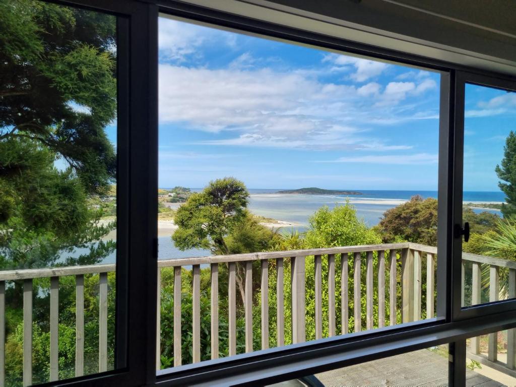 a view of the ocean from a house window at Tree House in Taieri Mouth