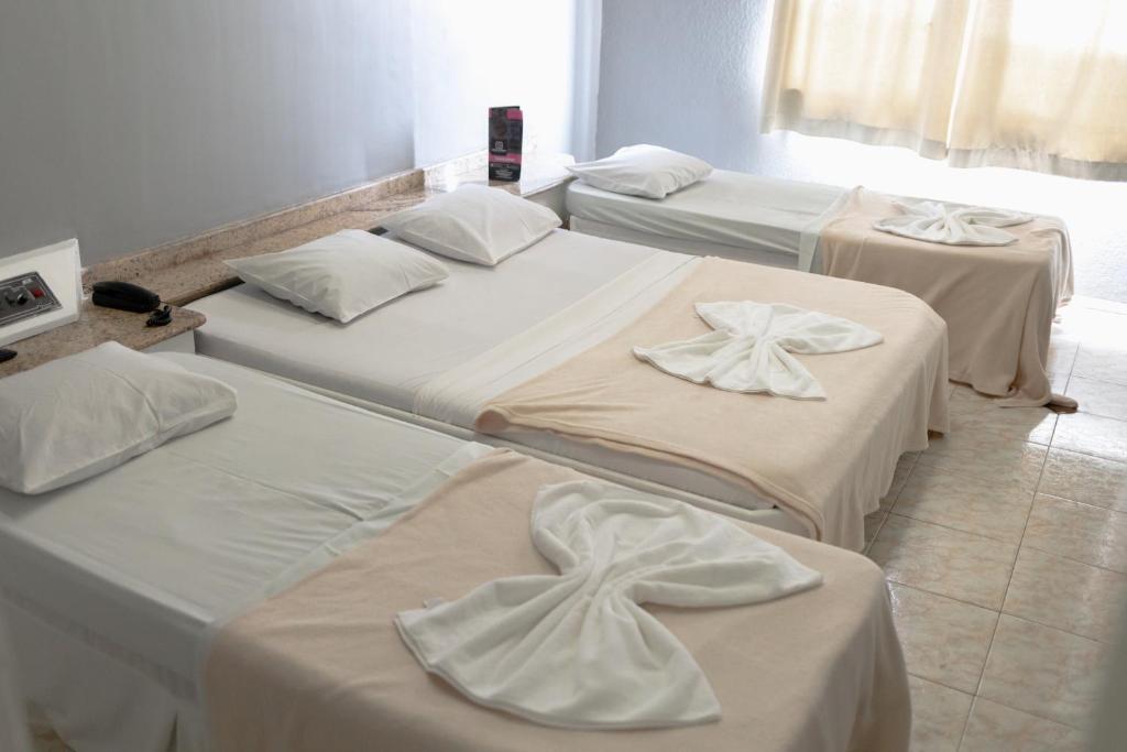 Un grupo de 4 camas en una habitación en Hotel Avenida en São João de Meriti