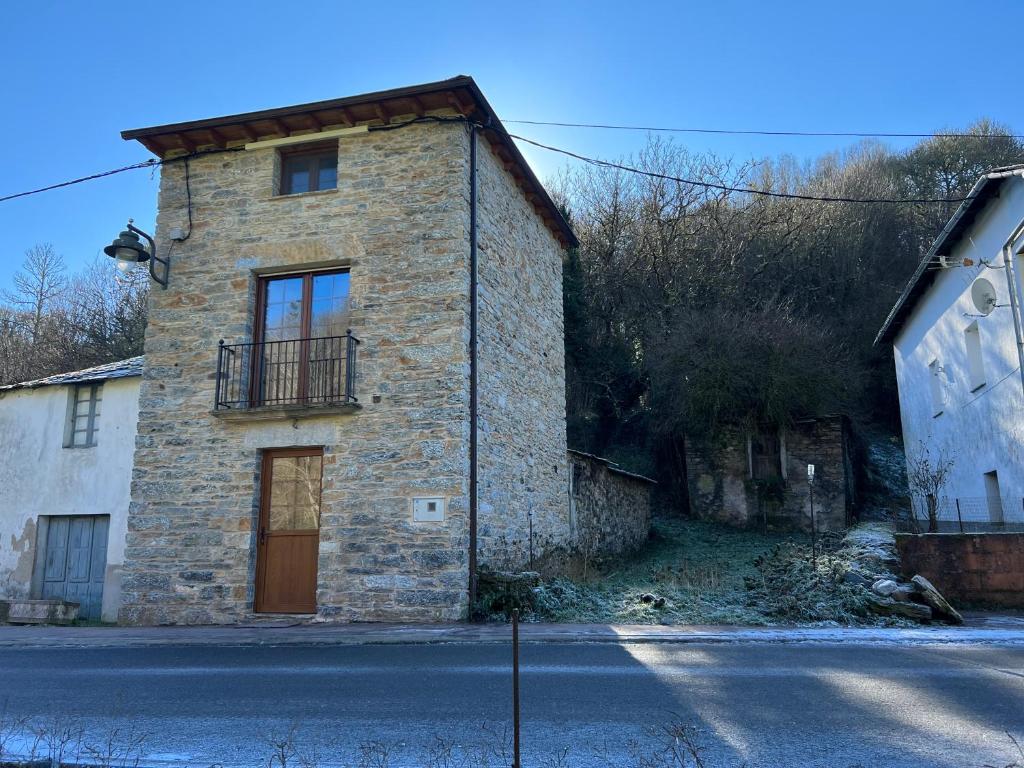 un edificio de ladrillo con un balcón en el lateral de una calle en Casa rural LA TORRE recién rehabilitada., en Las Herrerías