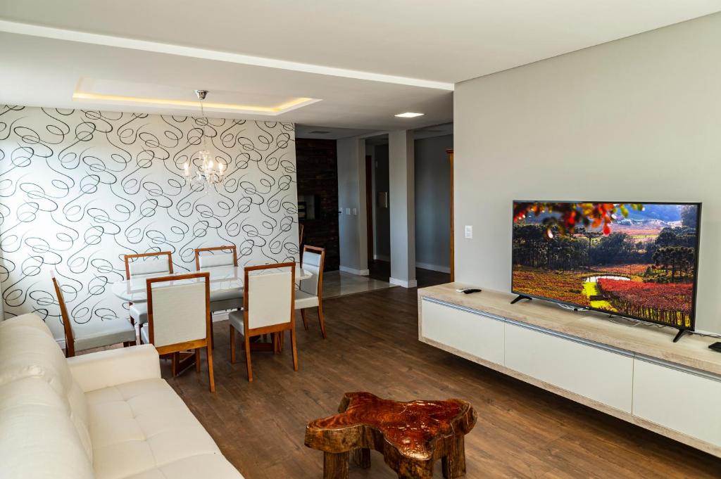 a living room with a white couch and a tv at Apartamento moderno no Vale dos Vinhedos in Monte Belo