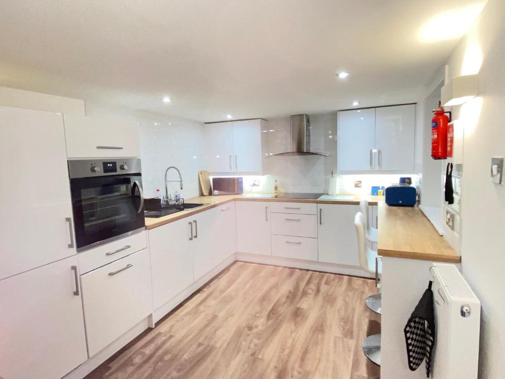 a kitchen with white cabinets and a wooden floor at Westons Hideaway, 2 Bed, Free Parking, 6 mins walk to beach, in Weston-super-Mare