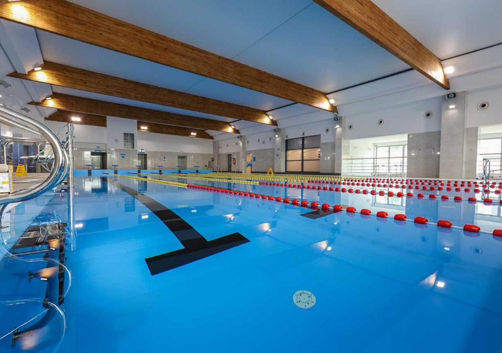 a large indoor swimming pool with blue water at Platinum Ostróda in Ostróda