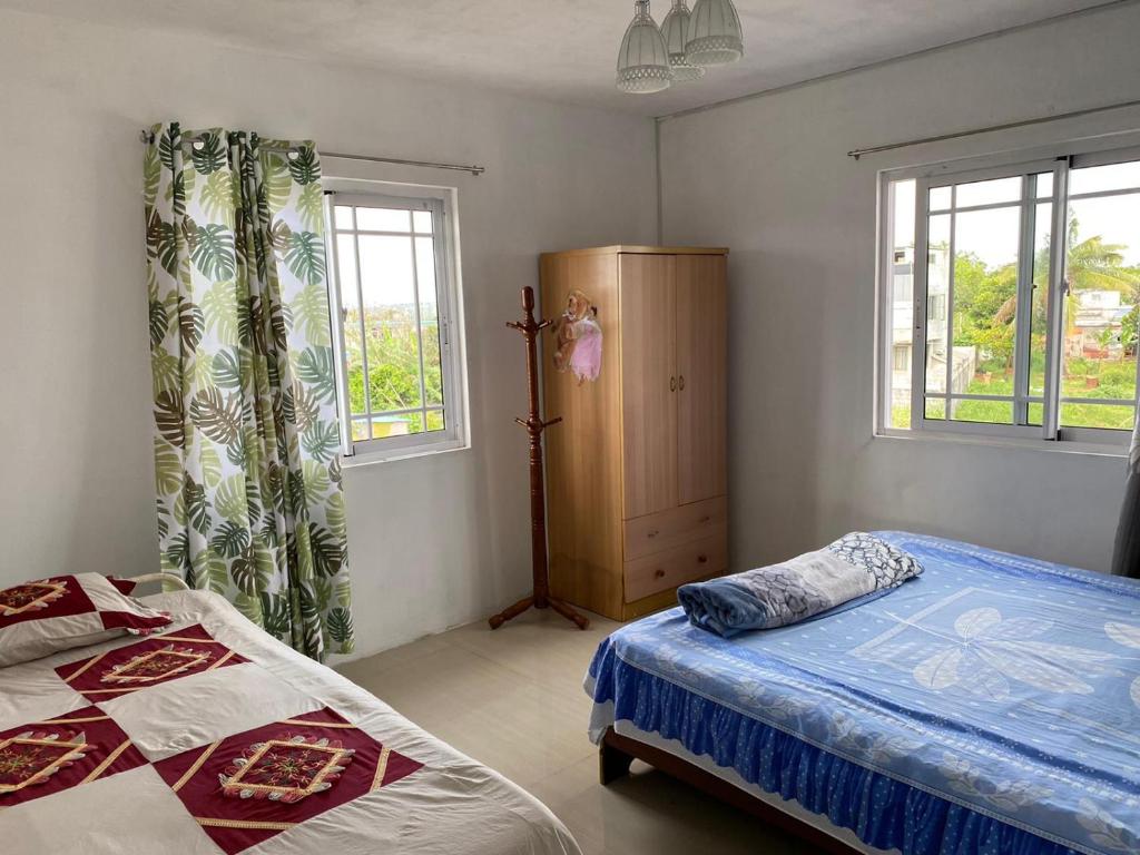 a bedroom with two beds and two windows at Green Discovery B&B Tamarind Falls 7 Cascades in Henrietta