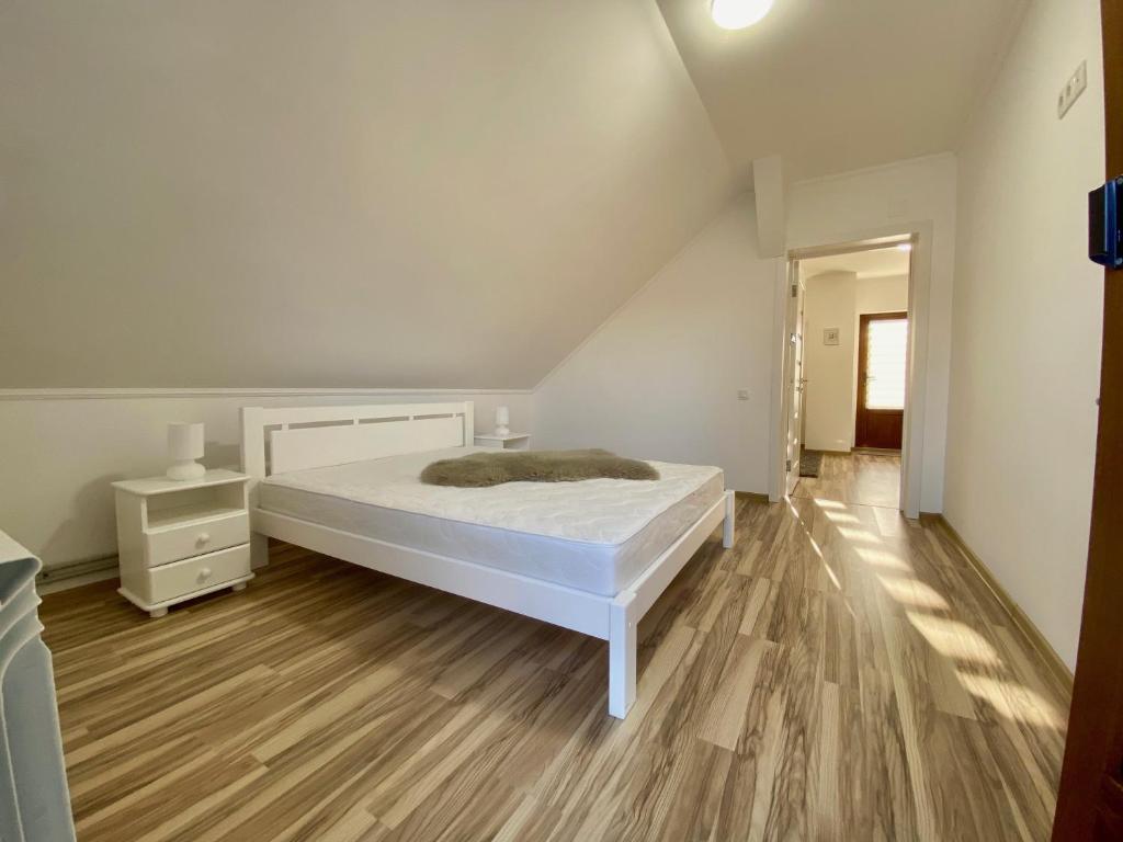Schlafzimmer mit einem weißen Bett und Holzboden in der Unterkunft Жива вода in Scheschory