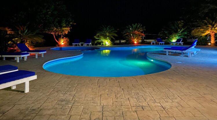 a swimming pool at night with chairs and benches at Brahma Blue Resort in San Pedro