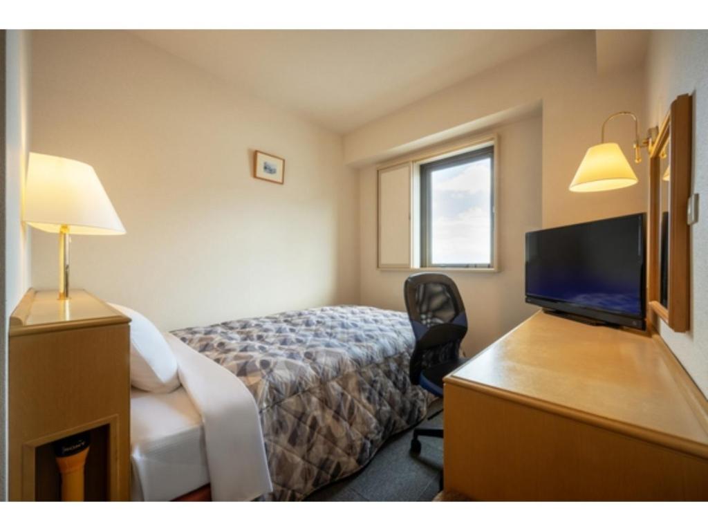 Cette chambre comprend un lit et un bureau avec une télévision. dans l'établissement Green Hotel Omagari - Vacation STAY 19280v, à Daisen