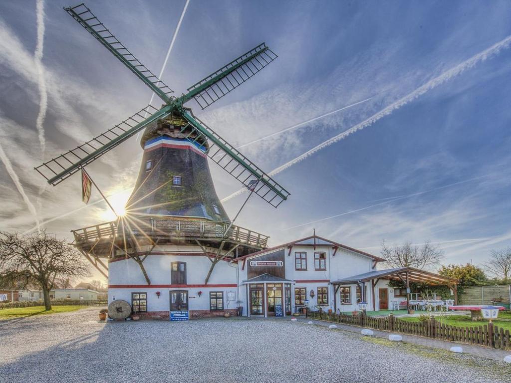 a building with a windmill in front of it at Ferienwohnungen Engelmühle in Nordstrand
