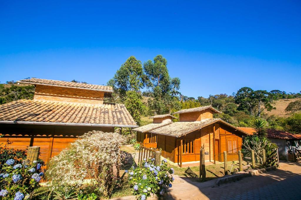 une maison et un bâtiment avec des fleurs devant dans l'établissement Chalés Belo Vale - Rua do Curro, à Conceição da Ibitipoca