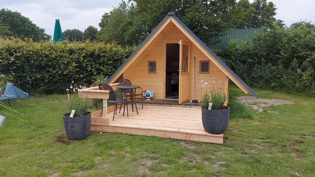 a small house with a wooden deck in a yard at Camping het Smitske in Drunen
