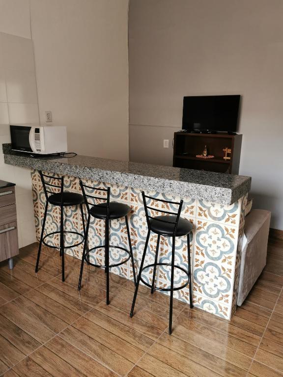 a kitchen with four bar stools at a counter at Casa do Diogo in Capitólio