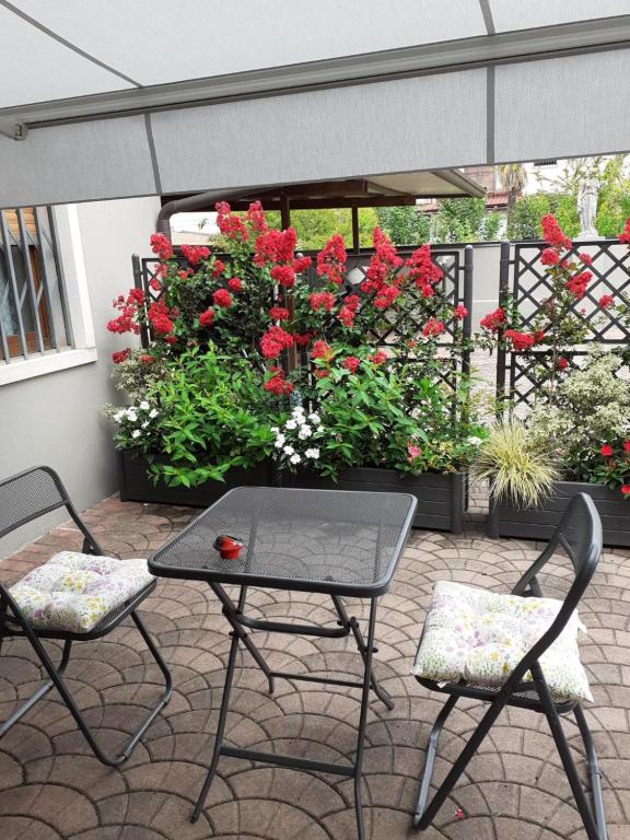 een patio met een tafel, 2 stoelen en bloemen bij La casa di Sabrina in Verona