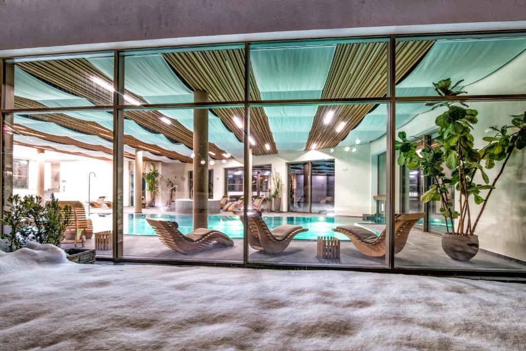 een huis met glazen wanden en een zwembad bij Sporthotel Zoll in Vipiteno
