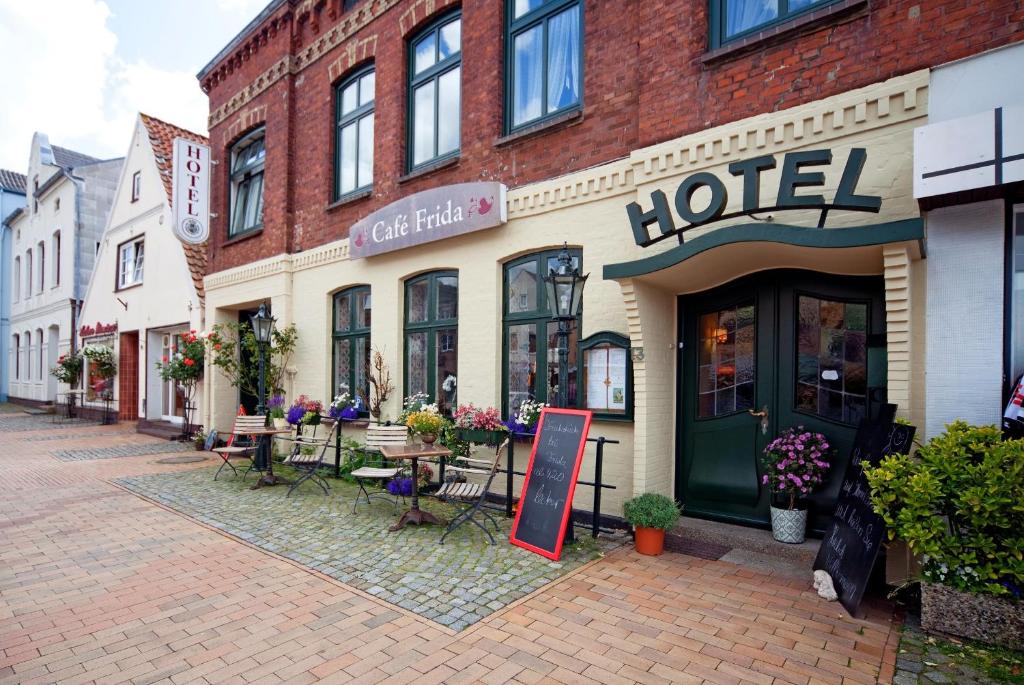 um edifício de hotel numa rua com mesas e cadeiras em Hotel Cafe Frida em Bredstedt