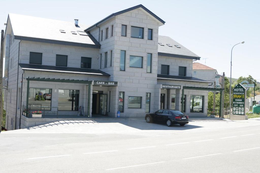 um edifício com um carro estacionado em frente em HOTEL BRUMA II em La Gudiña