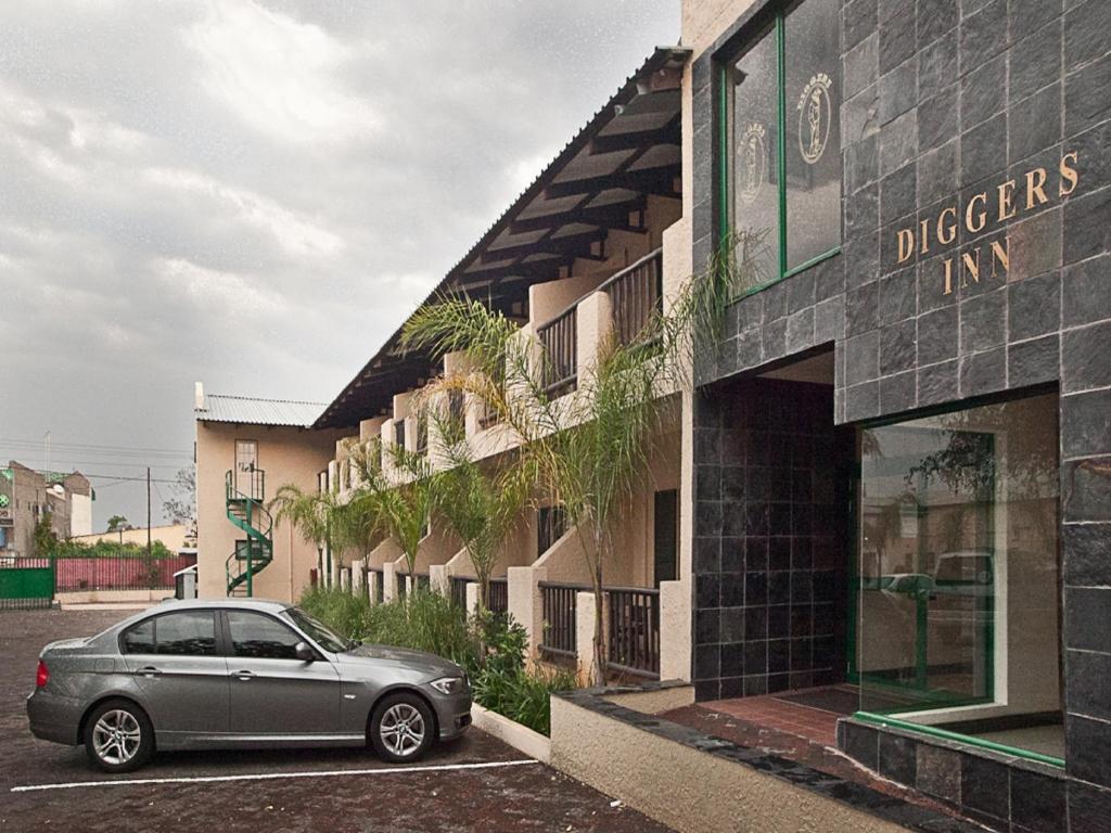 un'auto parcheggiata in un parcheggio di fronte a un edificio di Diggers Inn a Francistown