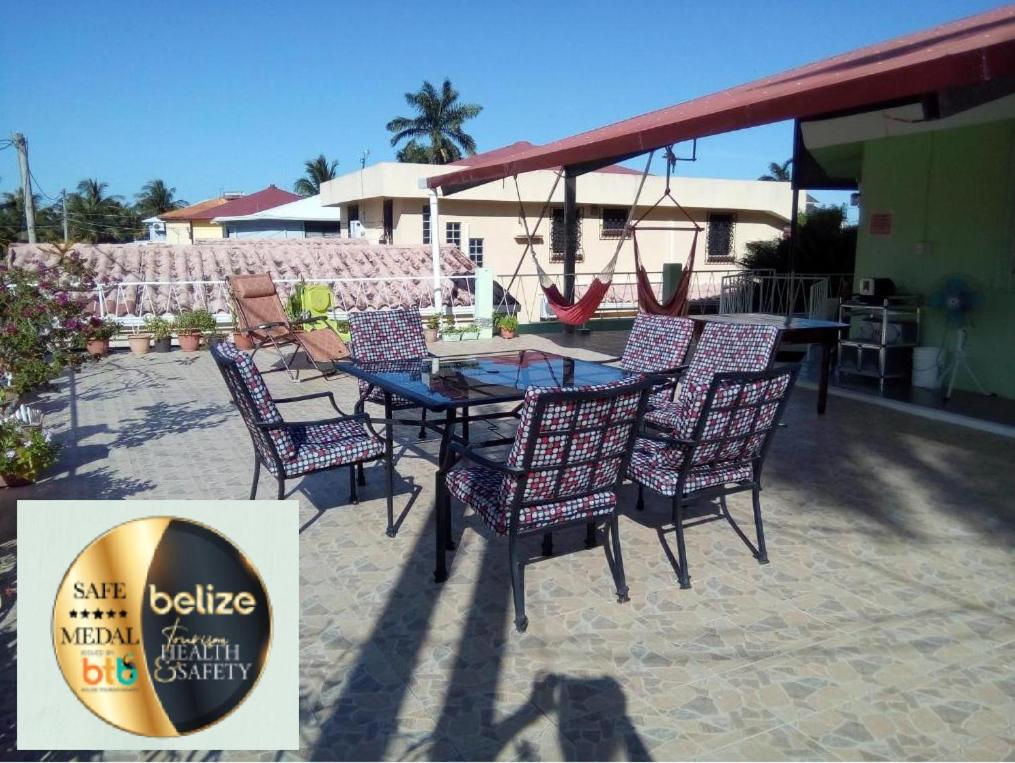 d'une terrasse avec une table, des chaises et une balançoire. dans l'établissement The Red Hut Inn, à Belize City