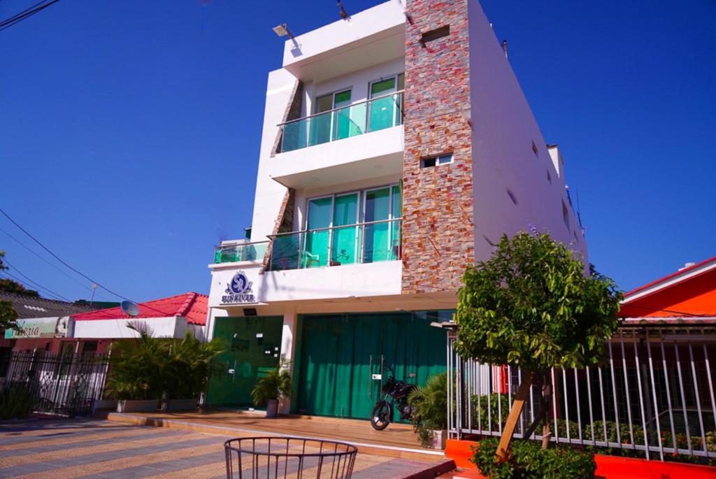 un edificio blanco alto con un árbol delante de él en Hotel Sun River, en Barranquilla