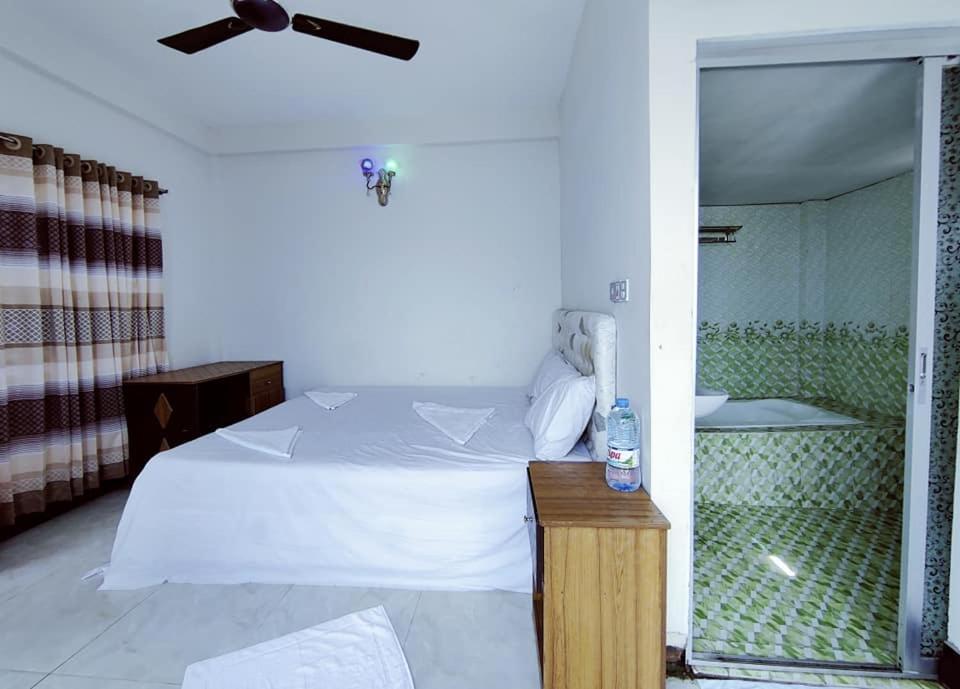 Un dormitorio con una cama blanca y un ventilador de techo. en Hotel Royal Beach & Restaurant, en Jaliapāra