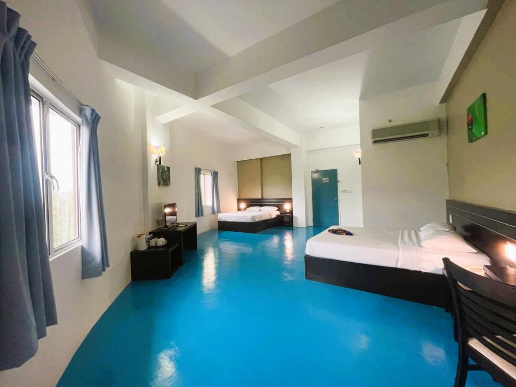 een kamer met 2 bedden en een blauwe vloer bij Kuala Melaka Inn in Pantai Cenang
