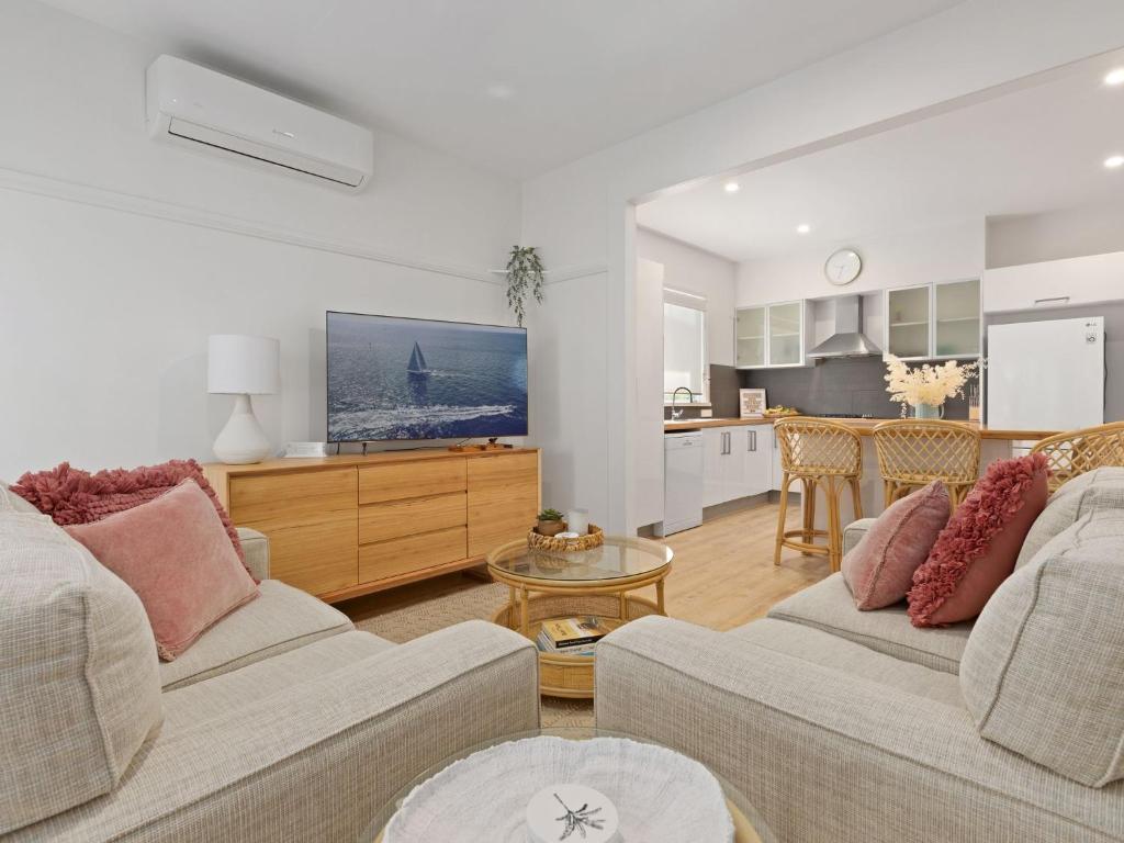 a living room with two couches and a kitchen at Husky Beach House by Experience Jervis Bay in Huskisson