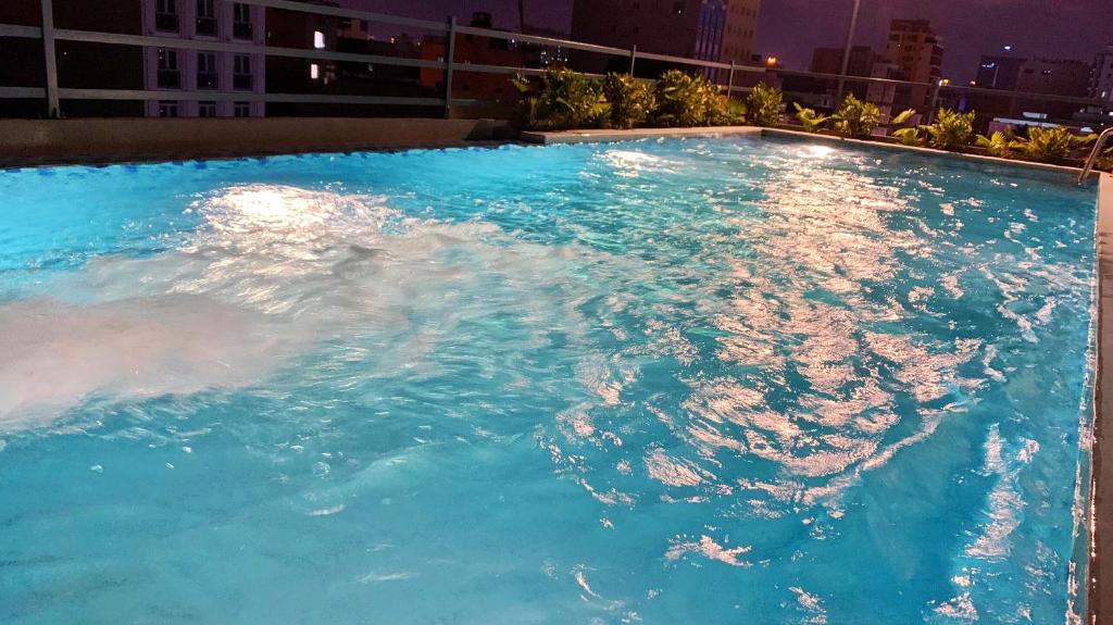 a large swimming pool with blue water at night at Marigold Hotel & Apartment in Danang