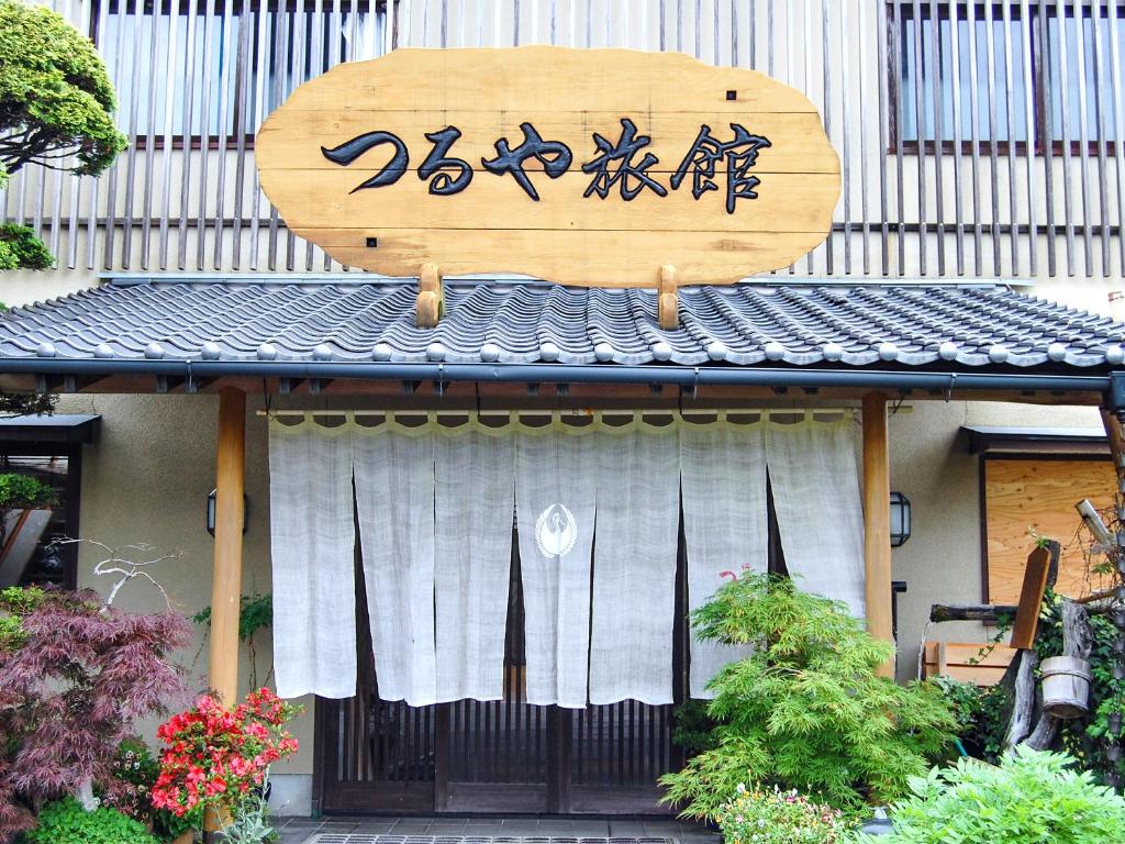 um sinal de madeira no lado de um edifício com uma cortina em AsoTsuruya em Aso